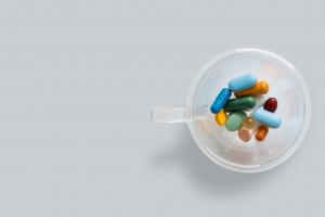 Medication capsules in a clear cup.